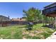 View of the backyard featuring a grill, wooden fence, grass and trees at 1584 S Fraser Way, Aurora, CO 80012