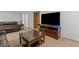 Finished basement living room showcasing large TV, brown furniture, and a wooden coffee table at 1584 S Fraser Way, Aurora, CO 80012