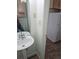 Cozy bathroom with pedestal sink, view into efficient kitchen and tiled flooring at 8023 Wolff St # F, Westminster, CO 80031