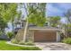 Front exterior of home with stone accents, lush landscaping, and an attached garage at 1540 W Briarwood Ave, Littleton, CO 80120