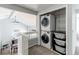 Laundry area with stacked washer and dryer, shelving, and baskets near open hallway and railing at 4483 S Fundy St, Centennial, CO 80015