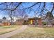 Charming brick home featuring a walkway to a pergola covered patio, a yellow door and a well-manicured lawn at 2576 Krameria St, Denver, CO 80207