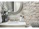 Elegant bathroom showcasing stone accent wall, oval mirror, and modern fixtures for a spa-like experience at 25548 E Fair Dr, Aurora, CO 80016