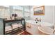Close-up on soaking tub with tiled walls and a shelf with towels in bathroom flooded with natural light at 1455 Flowers Ct, Erie, CO 80516