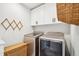 Efficient laundry room with side-by-side washer and dryer plus white upper cabinets and a woven laundry basket at 1455 Flowers Ct, Erie, CO 80516