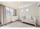 Bright Bedroom featuring a white crib, dresser, soft lighting, and large windows that offer ample natural light at 10196 Worchester St, Commerce City, CO 80022