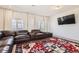 Comfortable living room with a large leather sectional, plush rug, bright windows, white curtains and a wall-mounted TV at 10196 Worchester St, Commerce City, CO 80022