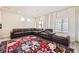 Spacious living room featuring a large brown leather sectional, plush rug, bright windows, and elegant white curtains at 10196 Worchester St, Commerce City, CO 80022