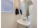 Charming powder room with a pedestal sink, round mirror, and a window providing natural light at 10196 Worchester St, Commerce City, CO 80022