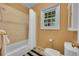 Bright bathroom features a shower-tub, window, toilet, beige wall, and striped floor mat at 29832 Dorothy Rd, Evergreen, CO 80439