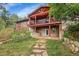 Back of house featuring stone steps, back patio and unique upper level deck at 29832 Dorothy Rd, Evergreen, CO 80439