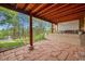 Stone tile patio with wood posts under a wood ceiling with a view of the surrounding pine trees at 29832 Dorothy Rd, Evergreen, CO 80439