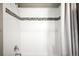 A tiled shower featuring white tiles and a decorative accent row with a chrome shower head and faucet at 23421 E Rockinghorse Pkwy, Aurora, CO 80016