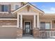 Close-up of the front porch featuring stone pillars, a black front door, and manicured landscaping at 20145 E Fair Ln, Centennial, CO 80016