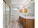 Bathroom featuring a glass-enclosed shower, modern vanity with double sinks, and wood-look flooring at 9214 Winona Ct, Westminster, CO 80031