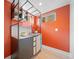 Modern kitchenette with stylish cabinetry and shelving on a bright orange wall in basement at 1401 Ash St, Denver, CO 80220