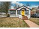Charming white and black Tudor-style house featuring a bright yellow front door, steps and a well-kept lawn at 1401 Ash St, Denver, CO 80220
