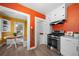 Kitchen with white cabinets, stainless steel oven, a breakfast nook, and orange accent walls at 1401 Ash St, Denver, CO 80220