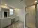 Bathroom featuring dual vanities, a glass-enclosed shower, and modern finishes at 767 Raindance St, Erie, CO 80516