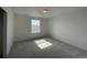 Minimalist bedroom with a large window providing ample natural light, carpet flooring, and neutral decor at 767 Raindance St, Erie, CO 80516