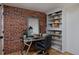 Cozy home office featuring a brick accent wall, built-in shelving, and modern desk, perfect for remote work at 2035 Bellaire St, Denver, CO 80207