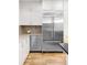 This kitchen boasts stainless steel appliances including a refrigerator and wine cooler, white cabinets, and hardwood floors at 659 Albion St, Denver, CO 80220