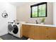 This is a laundry room with a window, front-loading washer and dryer, and wood cabinets at 659 Albion St, Denver, CO 80220