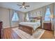This naturally lit main bedroom features wood laminate flooring, a ceiling fan, and a large bed at 6221 N Easton Ave, Frederick, CO 80504