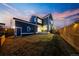 Backyard of a navy blue home with a well-manicured lawn, a wooden fence, and exterior lighting at 5965 Hanover St, Denver, CO 80238