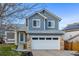 Charming two-story home featuring a large garage, blue siding, and well-maintained landscaping at 7586 Halleys Dr, Littleton, CO 80125