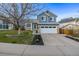 Two-story home with a well-kept front yard, blue siding, and a paved driveway leading to the garage at 7586 Halleys Dr, Littleton, CO 80125