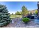Landscaped backyard with rock garden, patio, and a fire pit overlooking the lawn and black metal fence line at 27029 E Irish Pl, Aurora, CO 80016