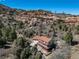 Aerial view of a home with a red tile roof, surrounded by trees and natural rock formations at 6601 Pike Cir, Larkspur, CO 80118