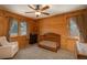 Bright bedroom with natural wood paneled walls, a crib, and large windows offering views of the surrounding landscape at 804 Clear Creek Rd, Evergreen, CO 80439