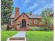 Charming brick home featuring a gabled roof, black trim, and lush green lawn at 1218 S Josephine St, Denver, CO 80210