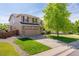 Charming two-story home featuring a well-manicured lawn, mature tree, and a two-car garage with a brick accent at 13180 Jasmine St, Thornton, CO 80602