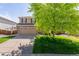 Charming two-story home featuring a well-manicured lawn, mature tree, and a two-car garage with a brick accent at 13180 Jasmine St, Thornton, CO 80602