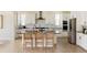 Modern kitchen boasts white cabinets, stainless steel appliances, a dark countertop island, and bar stool seating at 6506 Barnstead Dr, Castle Pines, CO 80108