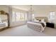 Bright main bedroom featuring a decorative chandelier, large windows, and a tufted headboard at 6506 Barnstead Dr, Castle Pines, CO 80108