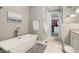 This bathroom has a freestanding tub, a white vanity, white tile flooring, and a walk-in closet for storage at 6899 Petunia Pl, Castle Rock, CO 80108