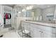 Bright bathroom features a marble countertop, dual sinks, a walk-in closet, a tiled shower, and a vanity chair at 6899 Petunia Pl, Castle Rock, CO 80108