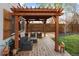 Backyard deck shaded by a wooden pergola featuring an outdoor seating area with privacy fence backdrop at 1891 S Madison St, Denver, CO 80210