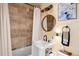 Neutral bathroom with white pedestal sink, exposed plumbing, round mirror, and earth-toned tiled shower at 1891 S Madison St, Denver, CO 80210