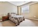 Bedroom with neutral colored walls, carpet, and a large window offering natural light for plants on the nightstand at 1853 S Marshall Cir, Lakewood, CO 80232