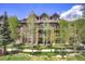 Attractive condo complex with stone accents, balconies, and sidewalks under partly cloudy, blue skies at 34 Highfield Trl # 112, Breckenridge, CO 80424