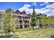 Attractive condo complex with stone accents, balconies, and manicured lawn under partly cloudy, blue skies at 34 Highfield Trl # 112, Breckenridge, CO 80424