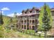 Exterior of a multi-story condominium with balconies, stone columns, and a lush landscape at 34 Highfield Trl # 112, Breckenridge, CO 80424