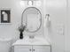 Close-up of updated bathroom vanity featuring a modern round mirror and decorative plant at 4003 Federal Blvd, Denver, CO 80211