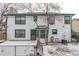A view of the home's backyard showcasing the white siding, green trim, and snowy grounds at 12107 E Vassar Dr, Aurora, CO 80014
