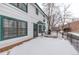 Rear view of home showcasing a large deck area, snow, and manicured shrubs at 12107 E Vassar Dr, Aurora, CO 80014